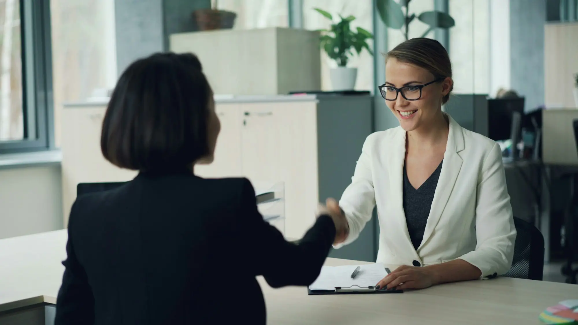 Two people shaking hands across a desk after a funding conversation