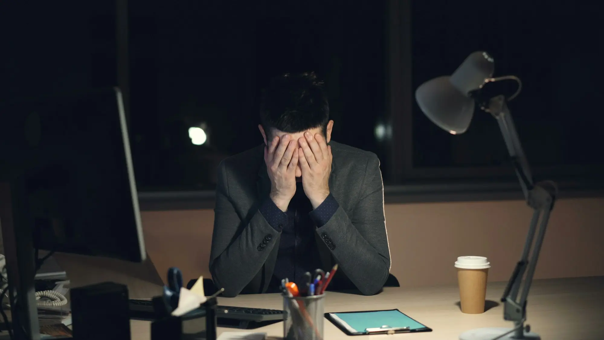 Business owner on the phone late at night in a workshop office, laptop open, looking focused